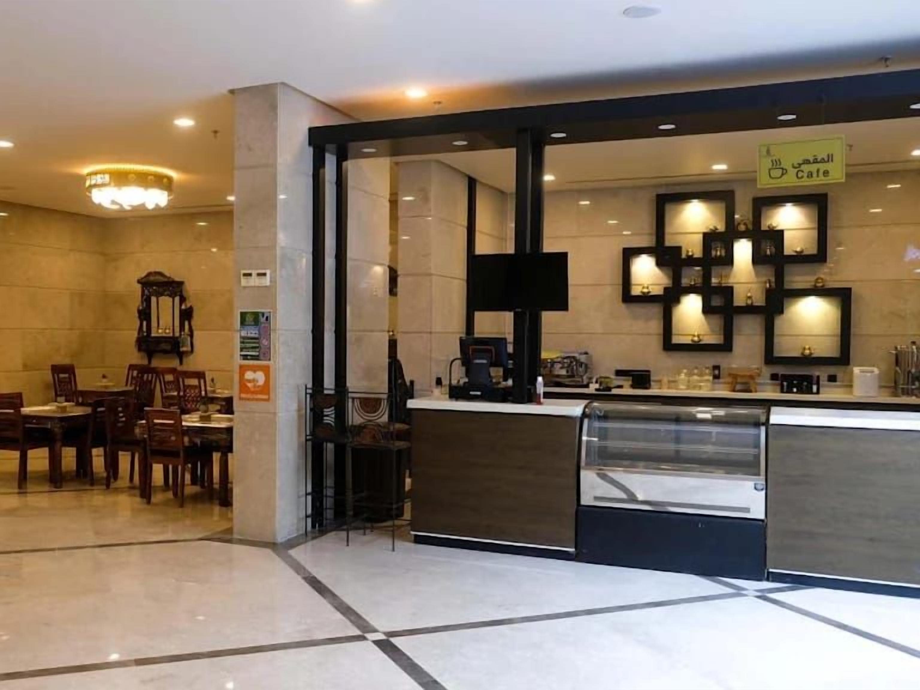 A modern cafe with a counter, seating area, and decorative wall lighting.