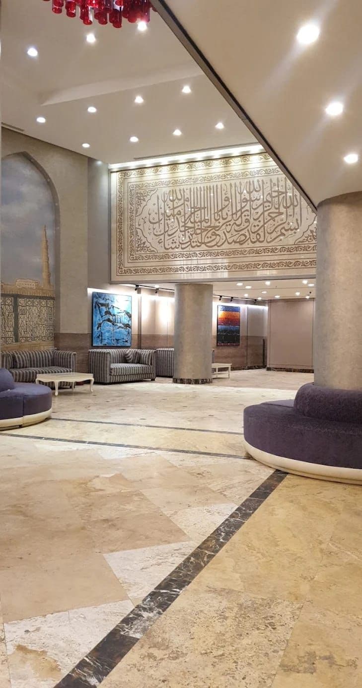 A spacious lobby with a high ceiling, patterned wall, and seating areas.