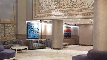 A spacious lobby with a high ceiling, patterned wall, and seating areas.