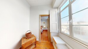 Un couloir étroit avec un banc en bois, une commode en bois et une grande fenêtre.