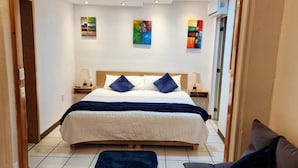 Ein Hotelzimmer mit einem großen Bett, zwei Nachttischen und Kunstwerken an den Wänden.