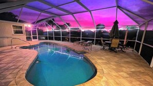 Piscina interior com borda curva, rodeada por um terraço coberto com área de estar.