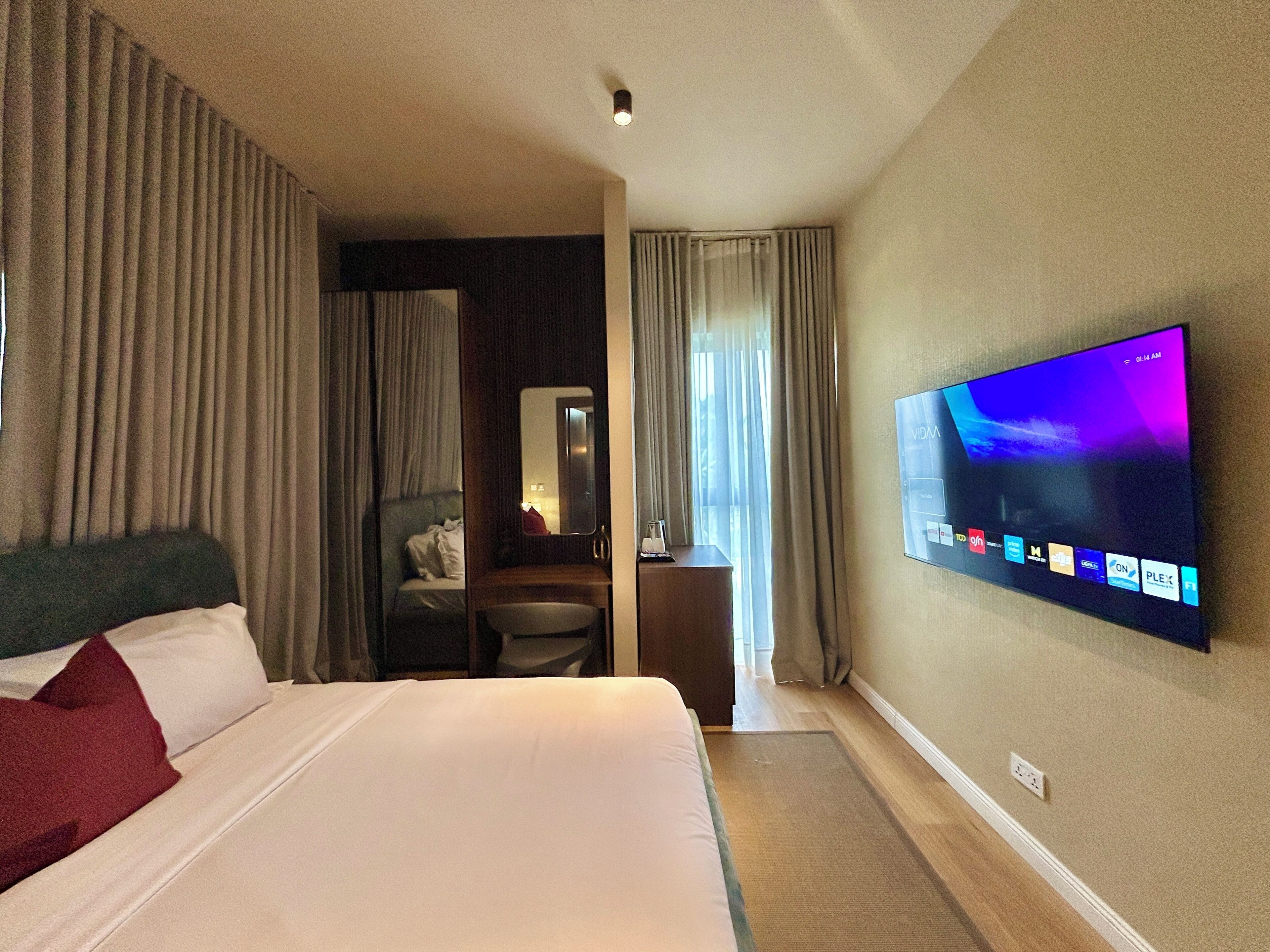 A hotel room with a bed, a desk, a TV, and a bathroom.