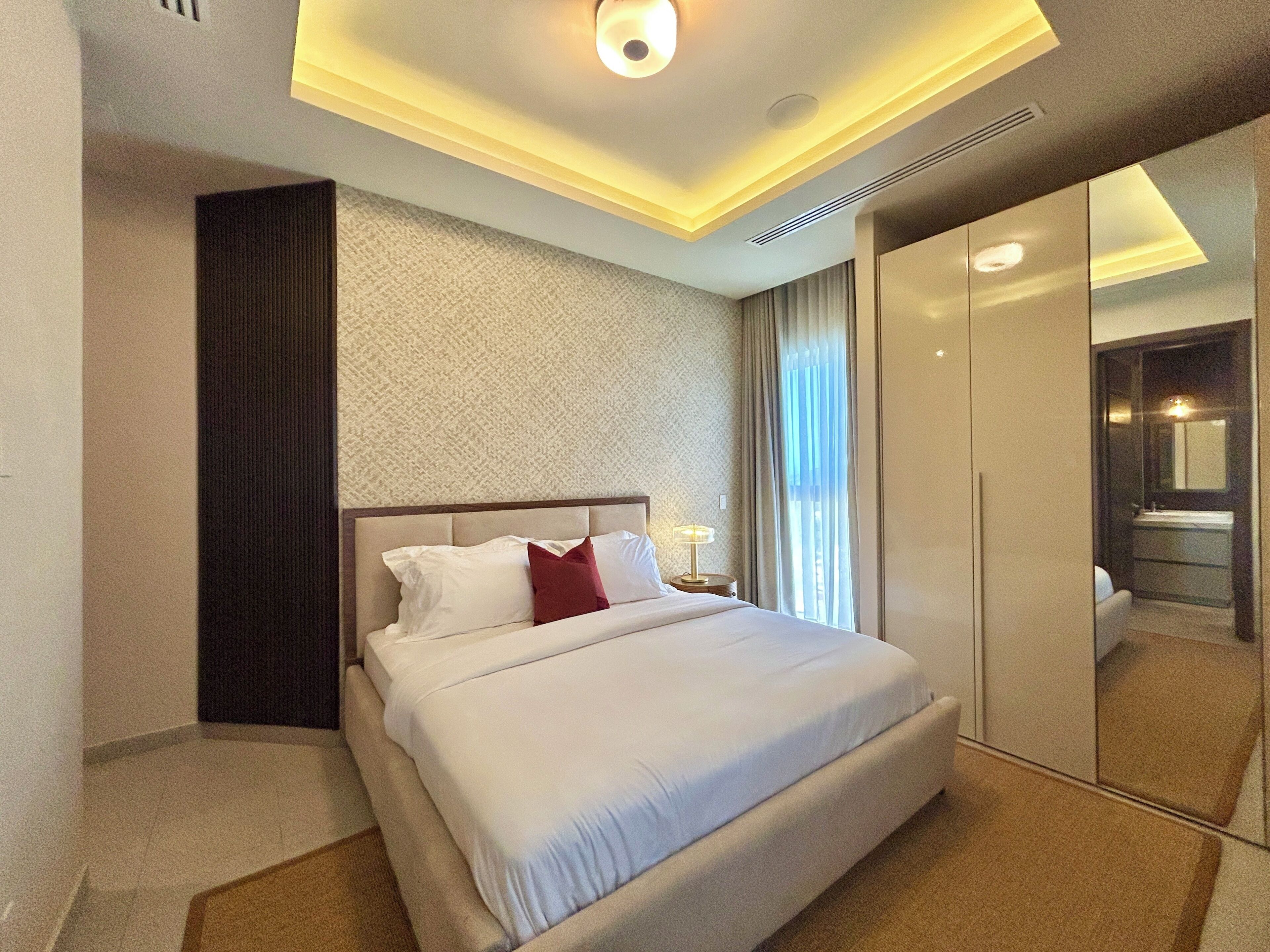 Une chambre d’hôtel comprenant un lit, une table de chevet, une lampe, une armoire et un miroir.