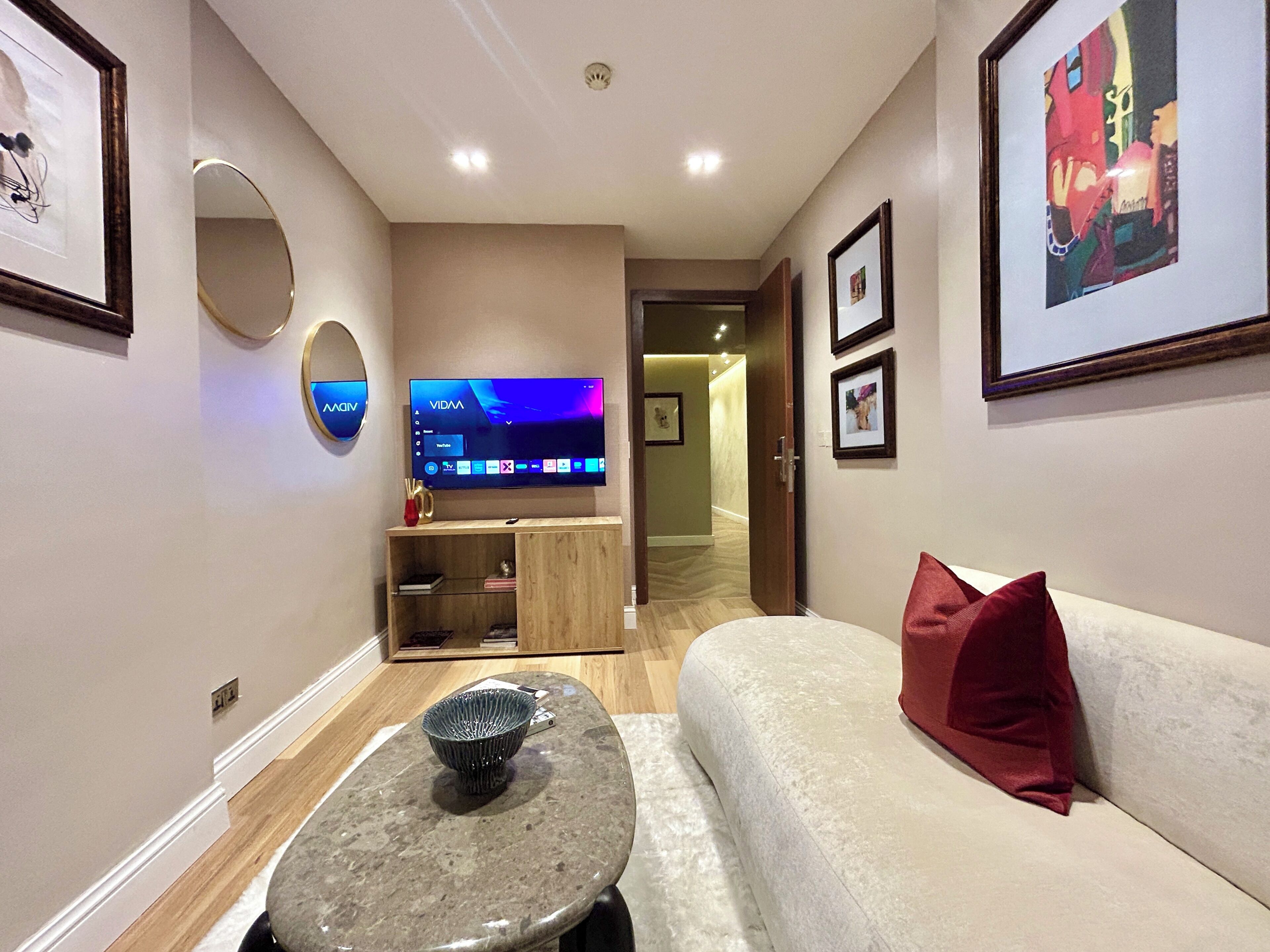A modern living room with a flat-screen TV, a sofa, a coffee table, and framed artwork on the walls.