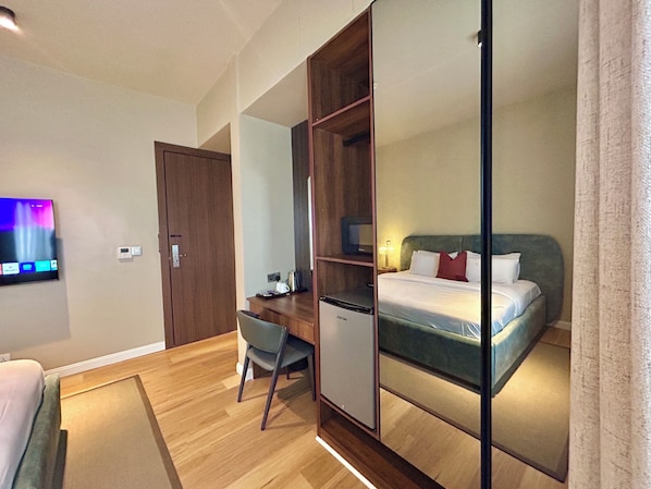 A hotel room with a bed, a desk, a chair, a television, and a wardrobe. - RIVERRUN RESIDENCE (Lagos)
