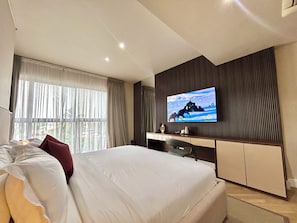Habitación de hotel moderna con una cama grande, un televisor de pantalla plana, un escritorio y vistas al exterior.