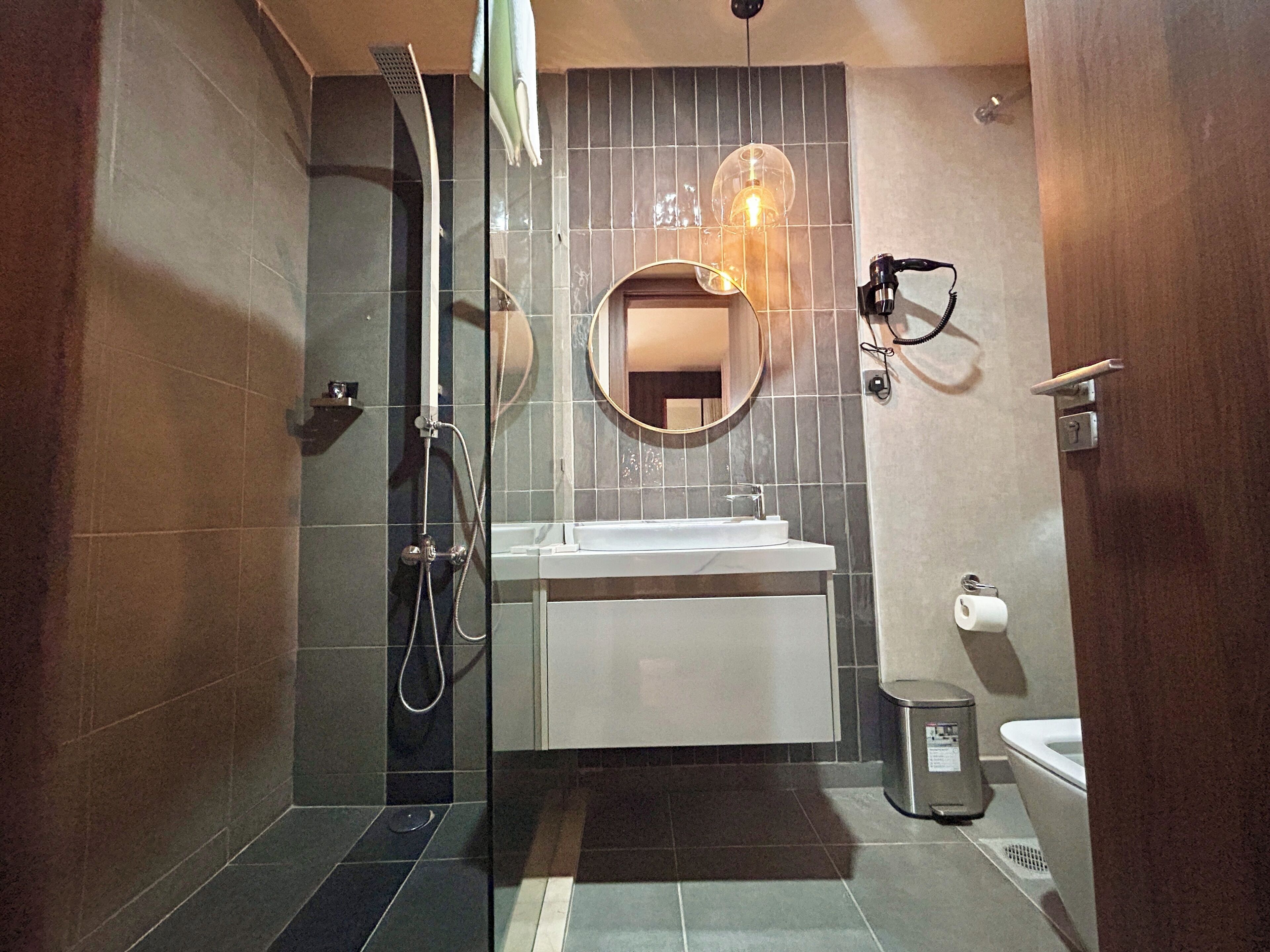 A bathroom with a shower, sink, mirror, and toilet.