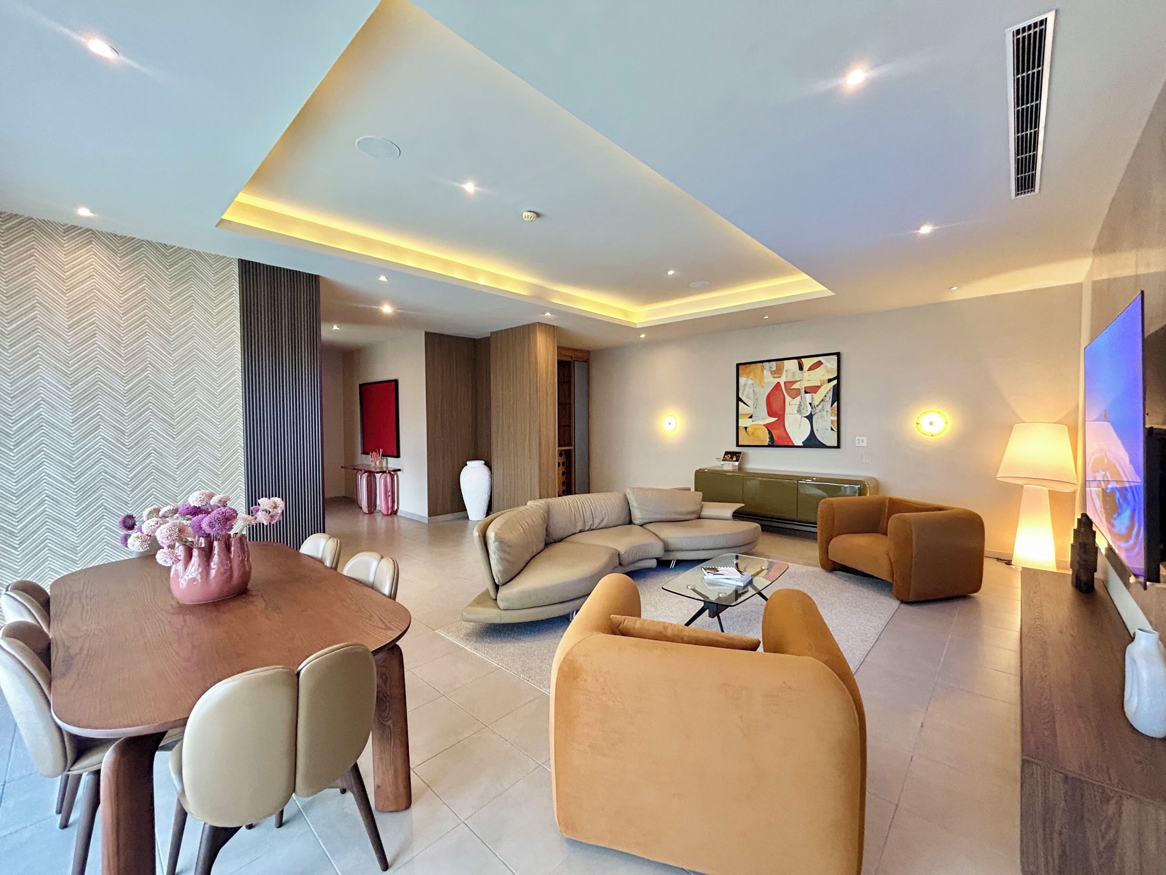 A modern living room with a sofa, armchairs, a coffee table, and a TV.
