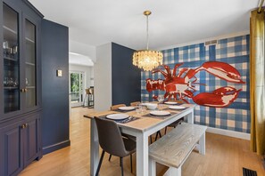 Een eetruimte met een geruit wandpaneel, een grote muurschildering van een krab en een kroonluchter.