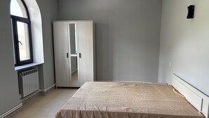 Une chambre à coucher avec un lit, une armoire, un radiateur et une fenêtre.