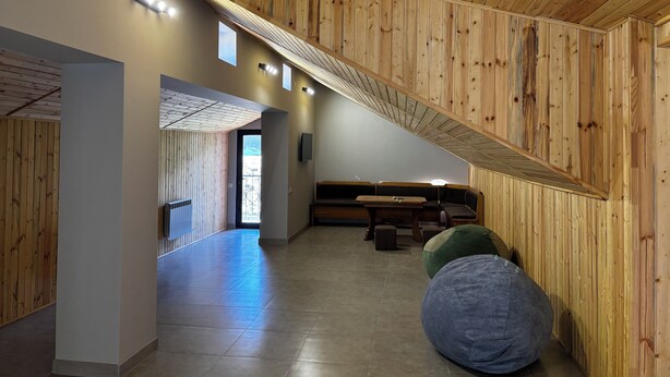 Un intérieur moderne avec un lambris en bois, un coin salon et une vue sur l’extérieur, visible à travers une porte.