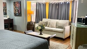 A modern hotel room with a bed, a sofa, a desk, and a dining table.