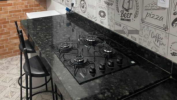 A kitchen with a black countertop, four burners, a microwave, and a wall decorated with food-related doodles.