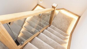 Un escalier en bois avec des rampes en verre et des marches recouvertes de moquette.