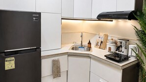 A modern kitchen with white cabinets, a stainless steel refrigerator, a built-in stove, and a coffee maker. - Cozy 29F Avida Riala IT Park Sea & City View (Cebu City)
