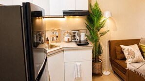 A compact kitchen with a refrigerator, stove, and coffee maker. - Cozy 29F Avida Riala IT Park Sea & City View (Cebu City)