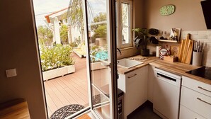 Une cuisine moderne équipée d’un lave-vaisselle, d’un évier et d’une fenêtre donnant sur un jardin.
