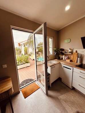 Eine moderne Küche mit Geschirrspüler, Spüle und Fenster mit Blick auf einen Garten.