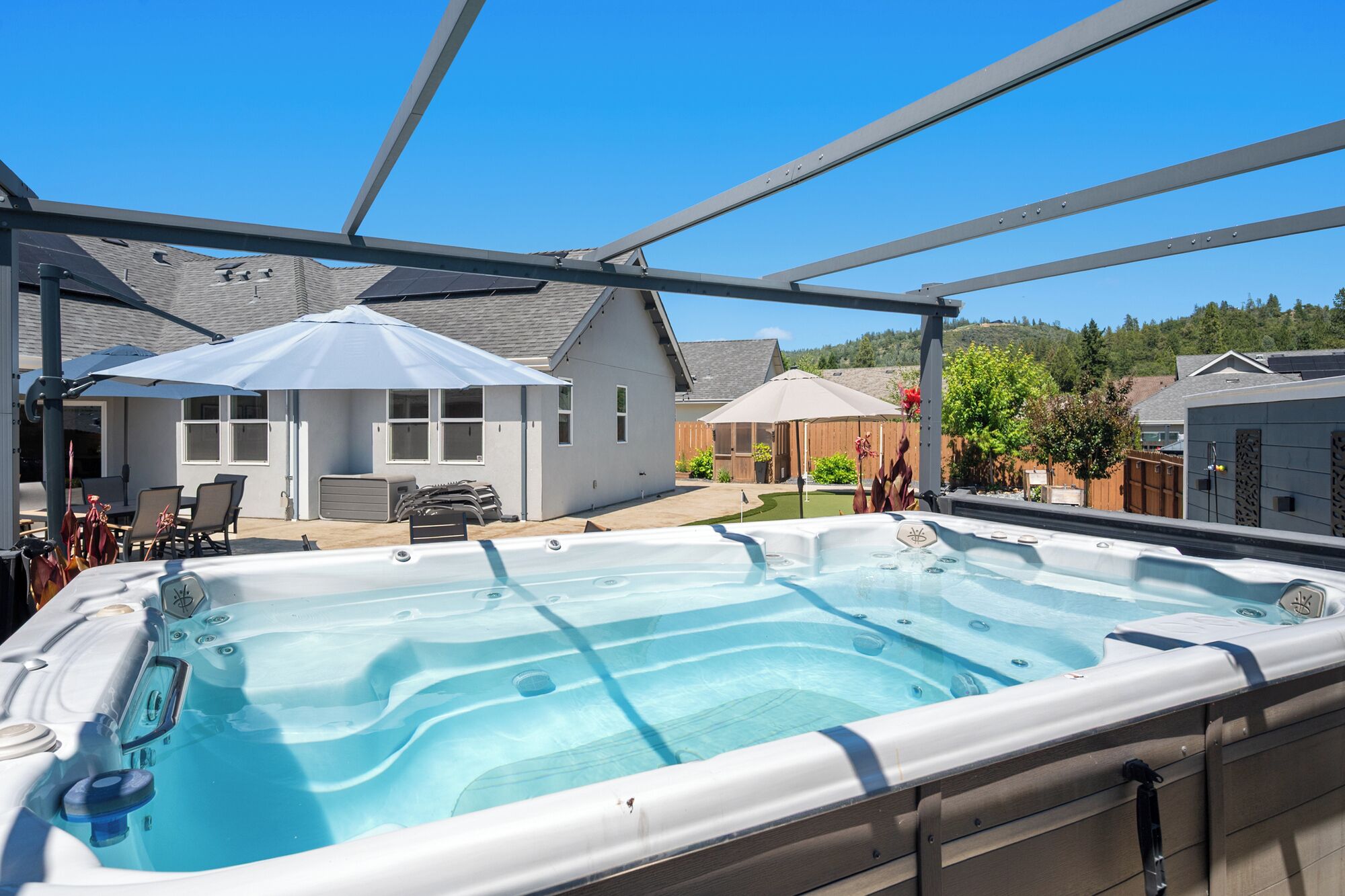 Un bain à remous doté d’un patio couvert, de mobilier d’extérieur et offrant une vue sur les maisons voisines.