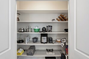 A kitchen with various appliances and storage shelves.