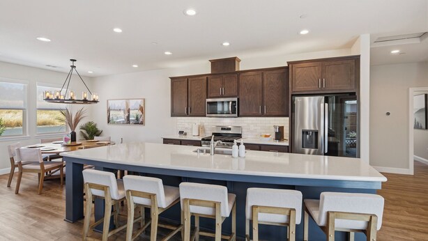 A modern kitchen with a large island, bar stools, wooden cabinets, stainless steel appliances, and a view of the outdoors. - Amazing new home- All the Amenities! (Murphys)
