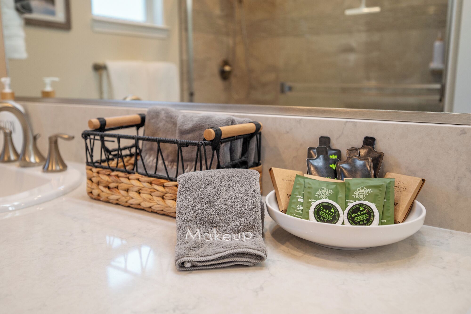 Un bagno con lavandino, asciugamano, cesto e una ciotola con articoli da toilette.