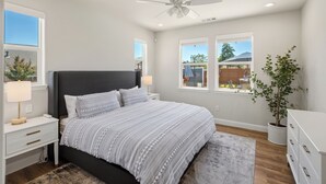A bedroom with a bed, nightstands, a ceiling fan, windows, and a potted plant. - Amazing new home- All the Amenities! (Murphys)