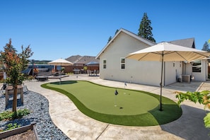 A residential backyard with a lawn, patio furniture, and a house.