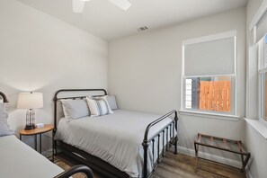A bedroom with a bed, bedside table, lamp, window, and a small wooden stool. - Amazing new home- All the Amenities! (Murphys)