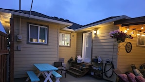 A covered patio with a blue picnic table, a small round stool, and a wooden bench.