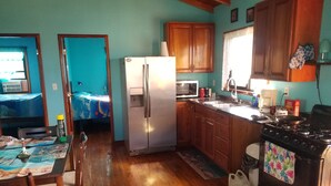 Cocina compacta con armarios de madera, un refrigerador, estufa y un comedor con mesa y sillas.