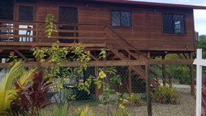 Una casa de madera con porche, escaleras y jardín cercado.