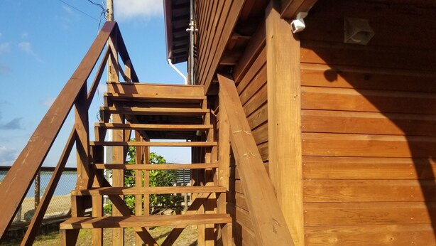 Una escalera de madera que conduce a un edificio con vista al cielo y al verdor.