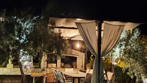 An outdoor patio with a stone table and chairs, a stone fireplace, and a pergola with curtains. - Double Room with Terrace and Sea View (Slano)