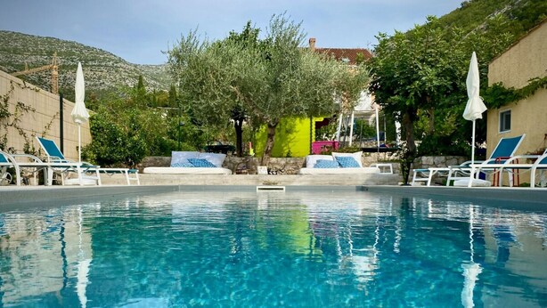 A clear swimming pool with lounge chairs and a view of a mountain. - Double Room with Terrace and Sea View (Slano)
