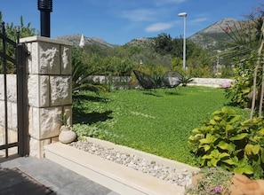 A landscaped garden with a stone wall, a metal chair, and a lamp post. - Double Room with Terrace and Sea View (Slano)