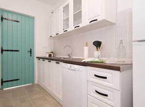 A kitchen with white cabinets, a teal door, a sink, and a dishwasher.