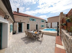 A courtyard with a pool, outdoor seating, and stone walls.