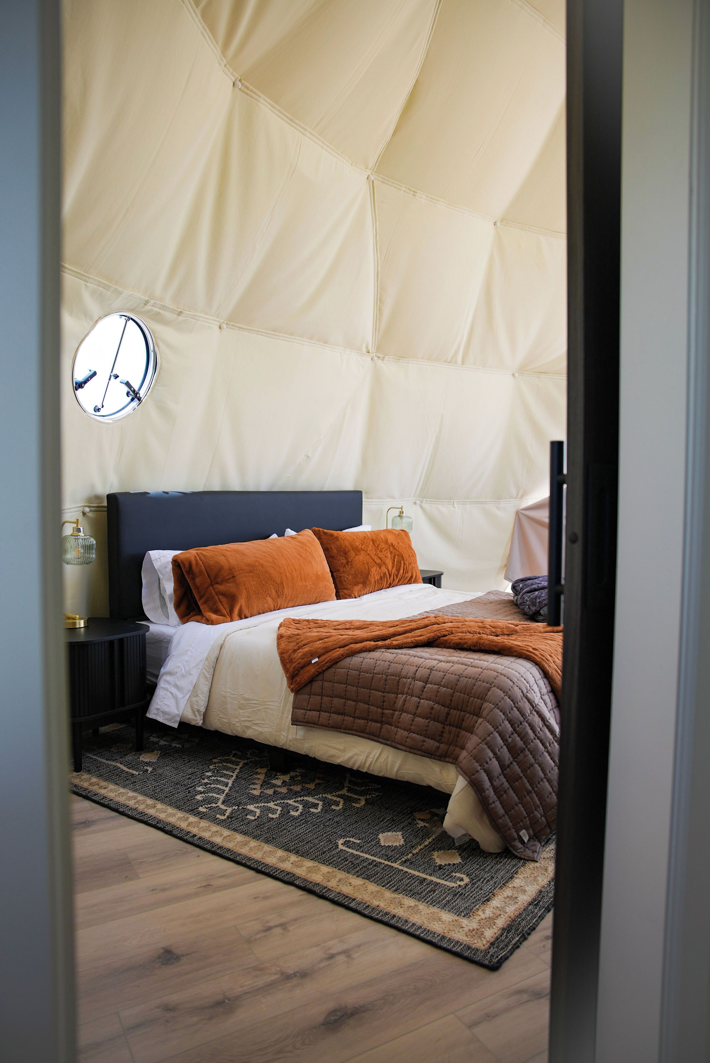 Ein Schlafzimmer mit Bett, Kissen, Nachttisch, Lampe und Teppich.