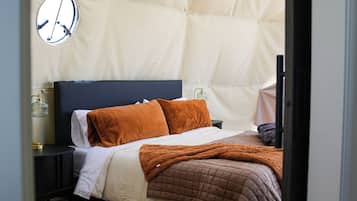 Ein Schlafzimmer mit Bett, Kissen, Nachttisch, Lampe und Teppich.
