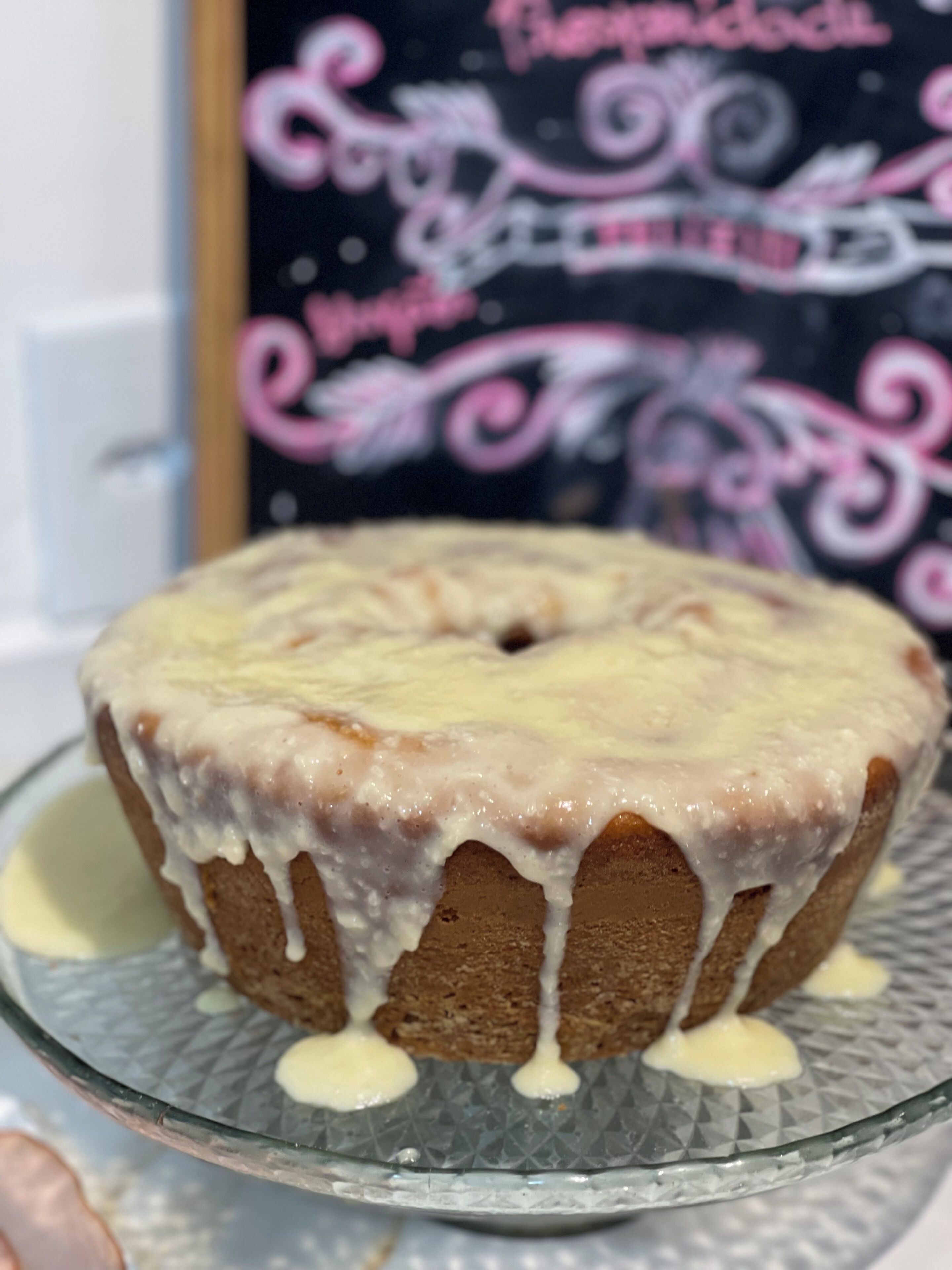 Un pastel con cobertura blanca sobre un plato de vidrio.