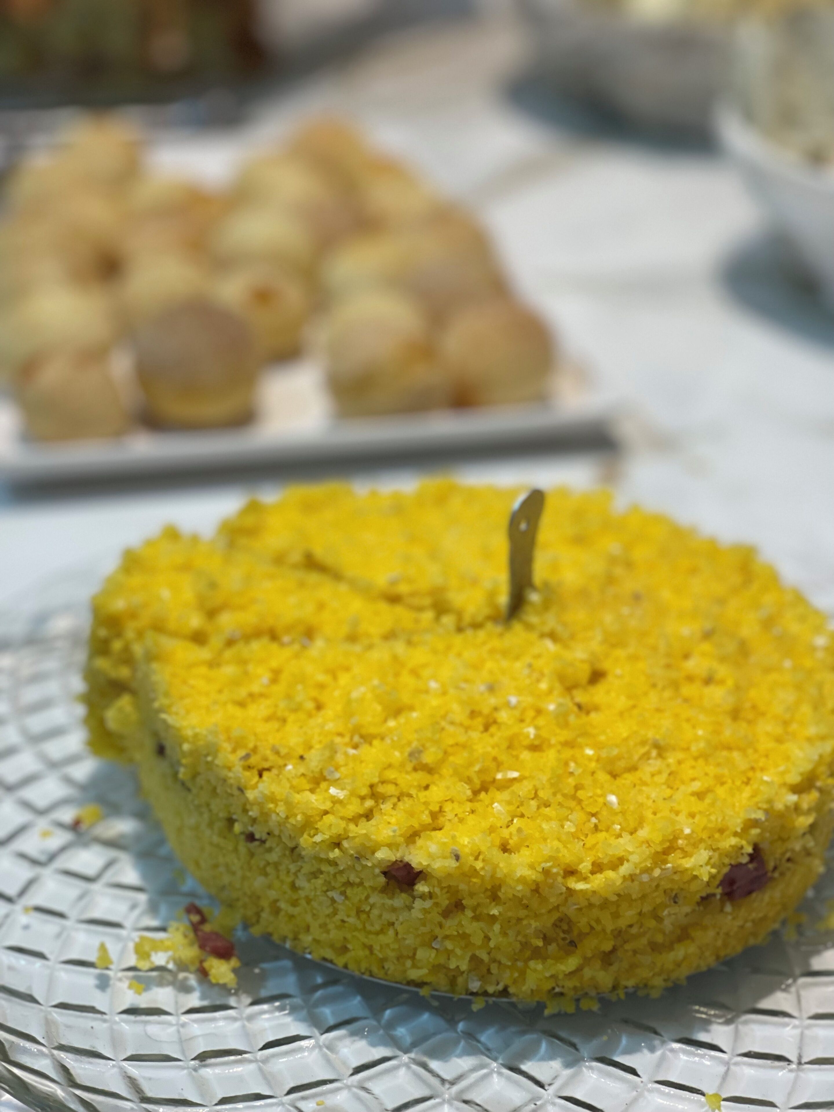 A yellow cake with a toothpick on a glass plate.