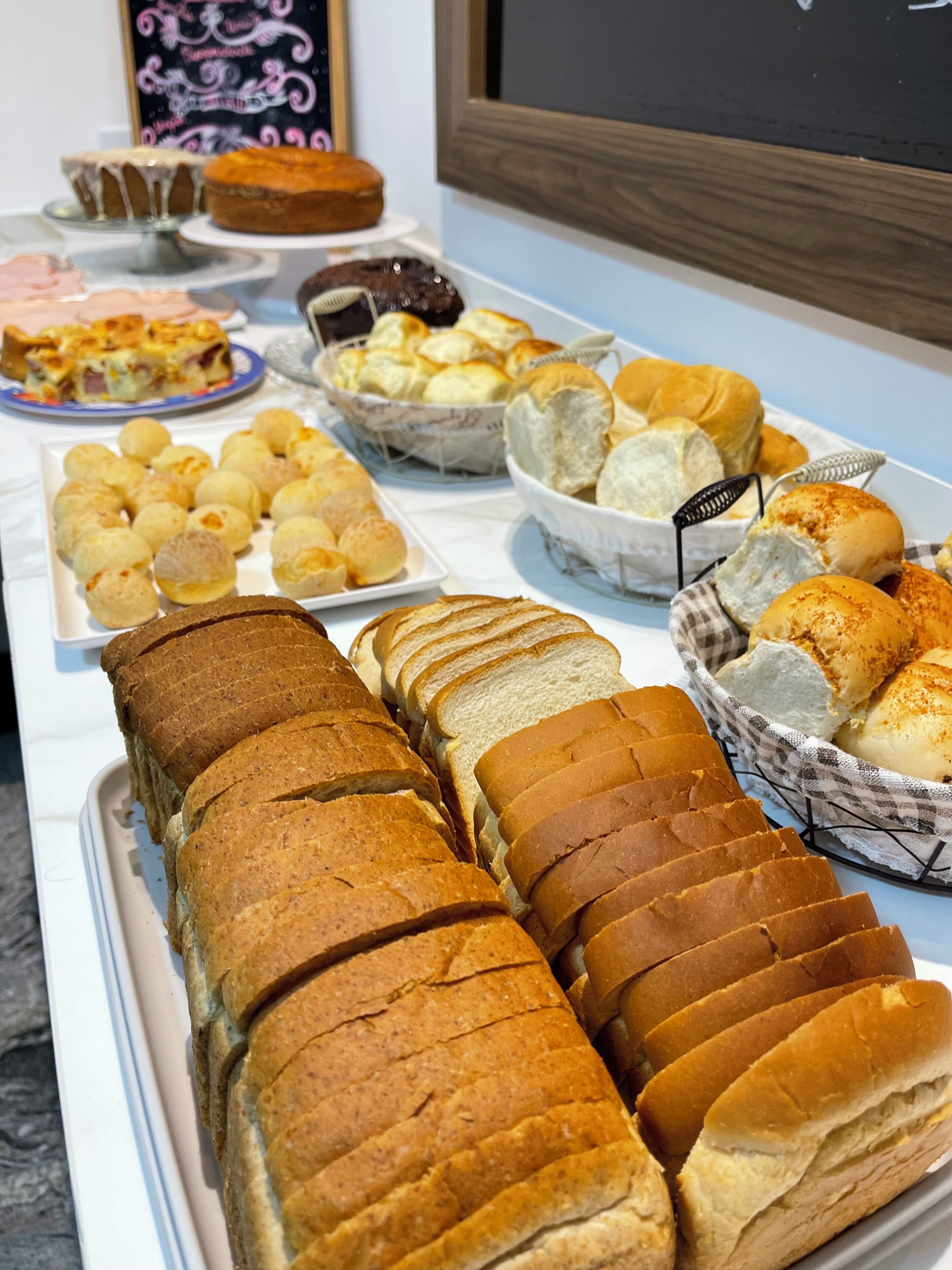 A buffet table with various breads, pastries, and a cake.