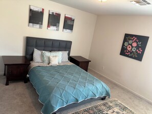 A bedroom with a bed, two nightstands, a headboard, and three wall art pieces. - Awesome 3-bedroom house with AC in pleasant Kingman (Kingman)