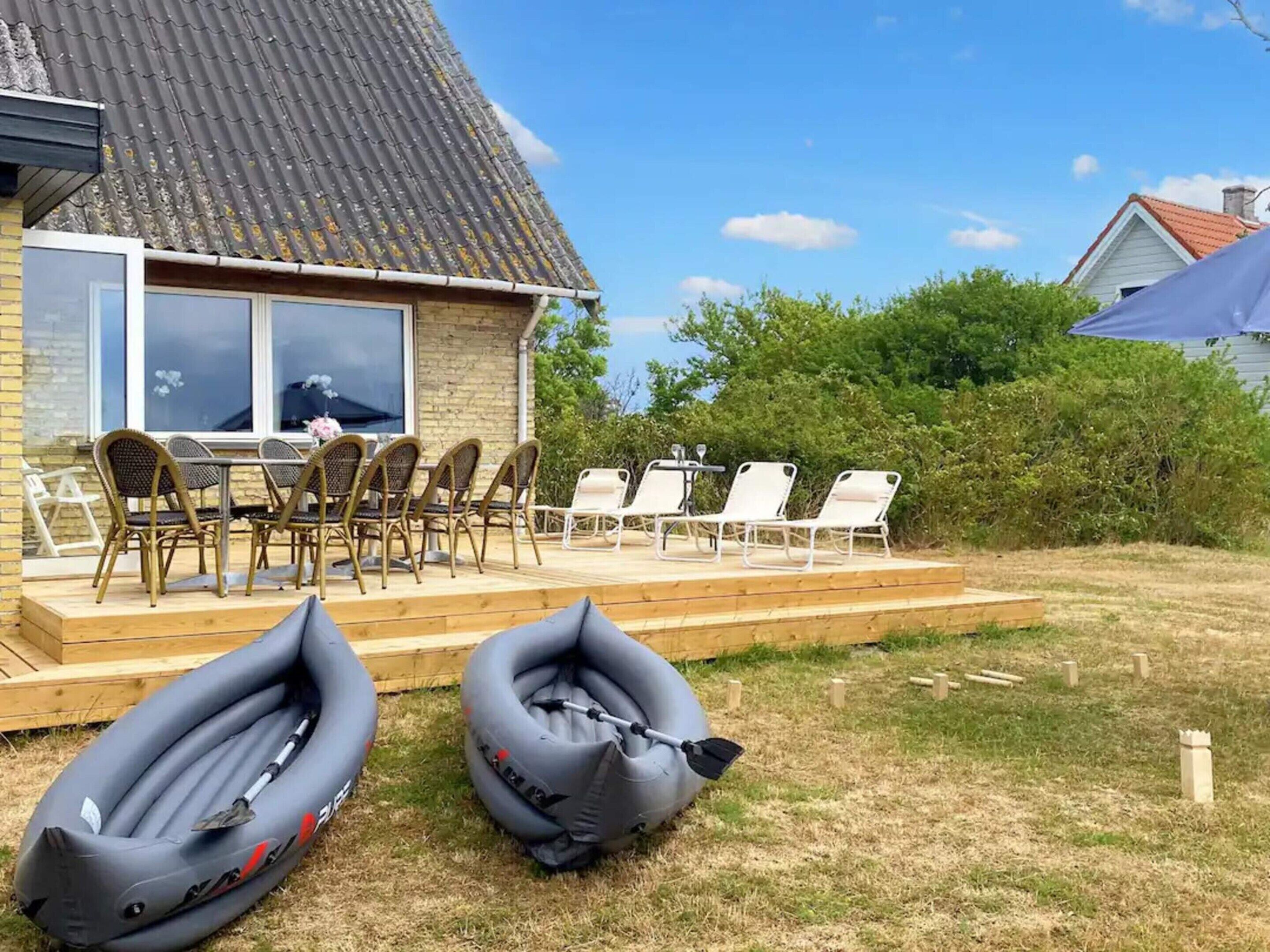 Une maison avec une terrasse, du mobilier d’extérieur et deux matelas gonflables.