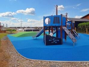 Ein Spielplatz mit Rutsche, Kletterbereich und einer Spielanlage im Schiffsdesign.