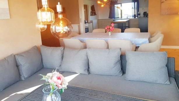 A modern living room with a sofa, dining table, and hanging light fixtures. - 5 Star Holiday Home in Femo (Maribo)