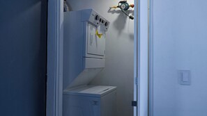 A laundry room with a washing machine and dryer, a water heater, and a control panel.
