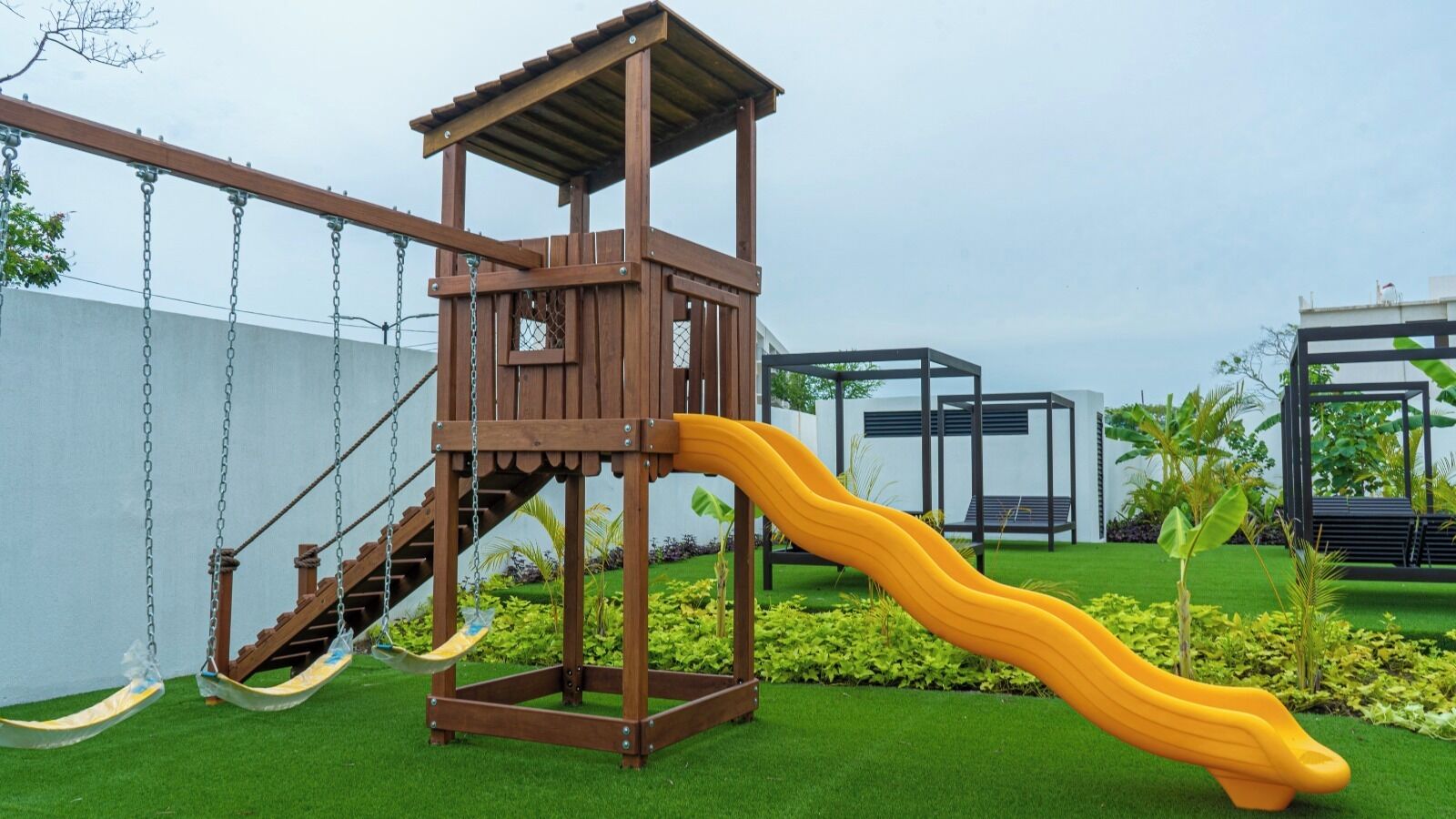 A playground with a wooden structure, a slide, and artificial grass.